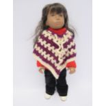 A vintage Sasha brunette girl doll dressed in knitted poncho, red jumper, black corduroy trousers