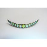 A crescent brooch set with thirteen graduated opals spaced by lines of old cut diamonds, 7.4cm long,