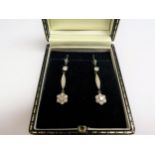 A pair of white gold diamond drop earrings, the drop as a flower hung from later 925 wire hooks (3.
