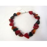 Designer row of chunky black red and amber type beads bearing a designer logo to one bead