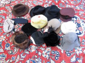 A box containing a variety of ladies' hats, a burgundy chauffeur's cap with badge, a forage cap
