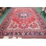 A red ground large Eastern wool rug, large central medallion flanked by multiple border, 360cm x