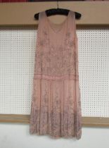 A 1920's pale peach chiffon beaded dress, the dress has a drop waistband and is decorated with