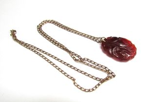 A carved red jade pendant with bird decoration 3.5cm x 2.5cm hung on a gold chain stamped 333,