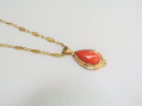 An 18ct gold bespoke made pendant with a pear shaped coral hung on a fancy 18ct gold chain