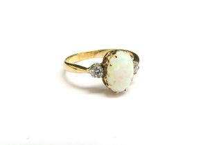 An 18ct gold opal and diamond ring, the oval cabochon opal flanked by diamonds. Size L/M, 2.3g