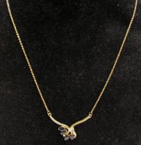 A gold neckchain having a scrolled bar set with four oval sapphires and four diamonds, stamped