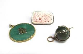 A circular jade pendant with 14k gold mount, a jade ball pendant and pink coral brooch