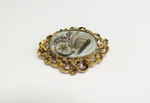 A Victorian memoriam brooch the centre oval glass panel with ornate flower and frond hair detail, in