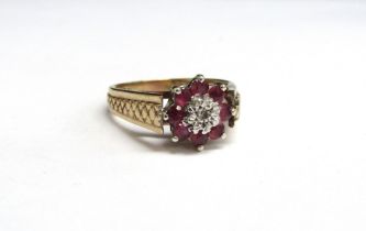 A 9ct gold ruby and diamond daisy ring with textured shoulders. Size O/P, 3.9g