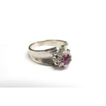 An 18ct white gold ring, London 1891, the central ruby framed by diamonds. Size R, 5.8g