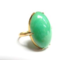 A gold ring set with a cabochon jadeite oval, oriental marks. Size K, 5.1g