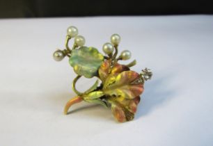 A gold brooch having leaves and flower in frosted pale enamels with pearl "berries" and old cut