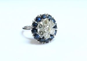 An 18ct white gold sapphire and diamond cluster, the central diamond framed by six further