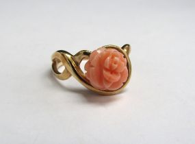 A gold ring with a carved coral rose in open scroll shoulders, stamped 14k. Size P, 3.5g