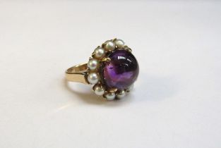A gold amethyst and pearl ring, the central cabochon amethyst framed by pearls, 17mm diameter