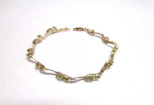 A gold wavy link bracelet set with marquise cut pale green stones, stamped 375, 19cm long, 4.3g