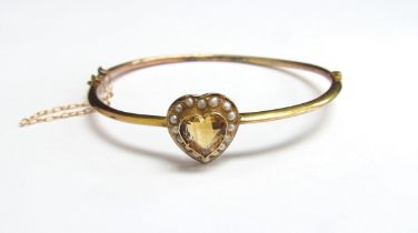 A gold hinged bangle with a central heart shaped citrine framed by seed pearls, unmarked, 5.5cm x