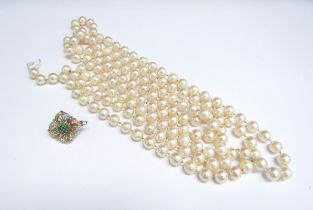 A single strand of pearls with a detached 9ct gold emerald and diamond clasp, 134cm long