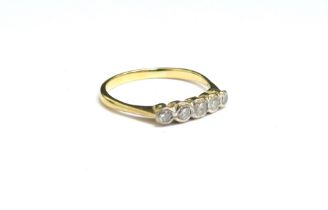 A gold ring with five graduated diamonds in rubover setting, stamped 18ct. Size R, 2.2g