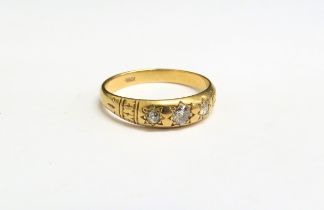 An 18ct gold three stone diamond gypsy ring. Size U, 4.1g