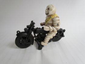 A reproduction cast Michelin Man riding a motorcycle - missing handle bars