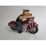 A cast reproduction Popeye riding a motorcycle figurine