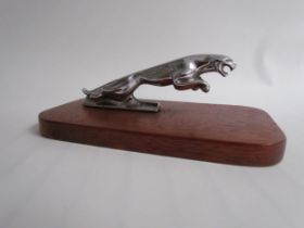 A chromed leaping Jaguar mascot mounted on a wooden plinth