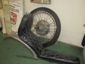 A motorcycle wheel with tyre and a motorcycle seat with attached mudguard