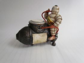 A cast reproduction Michelin Man sitting on a compressor