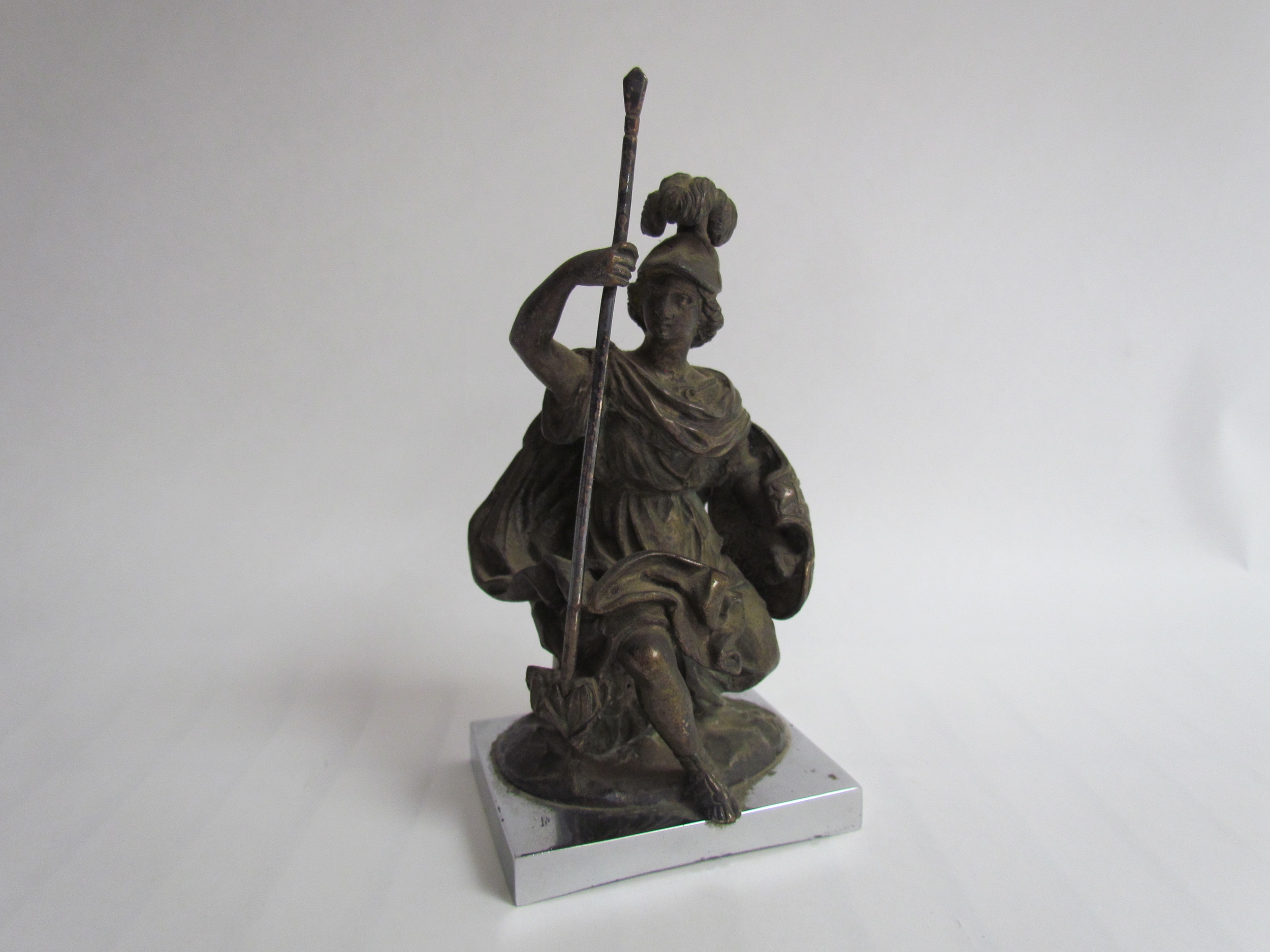 A bronze mascot in the form of a classical figure, possibly Athena goddess of wisdom