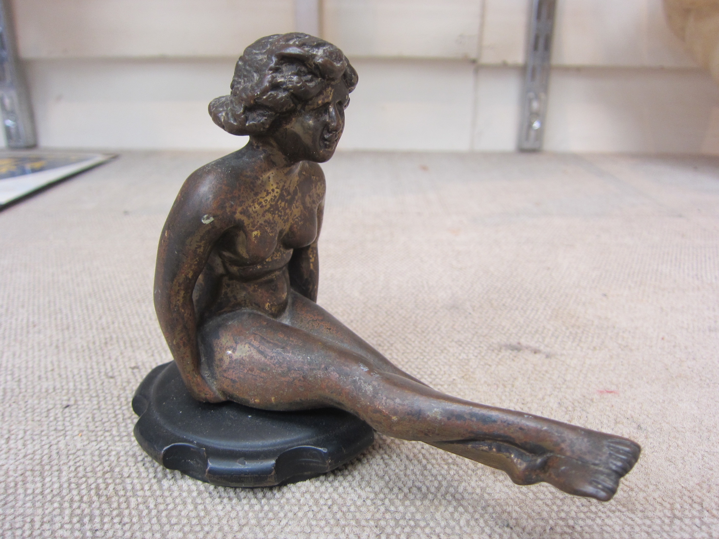 A bronze car radiator mascot circa 1900-1930, in the form of a seated naked lady