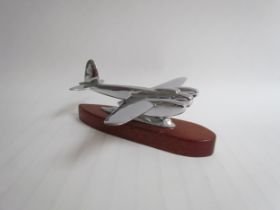 A chromed mascot of a WWII Mosquito mounted on a wooden plinth