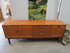 A teak sideboard with twin cupboard doors, fall flap door and three drawers. 206cm x 49cm x 80cm