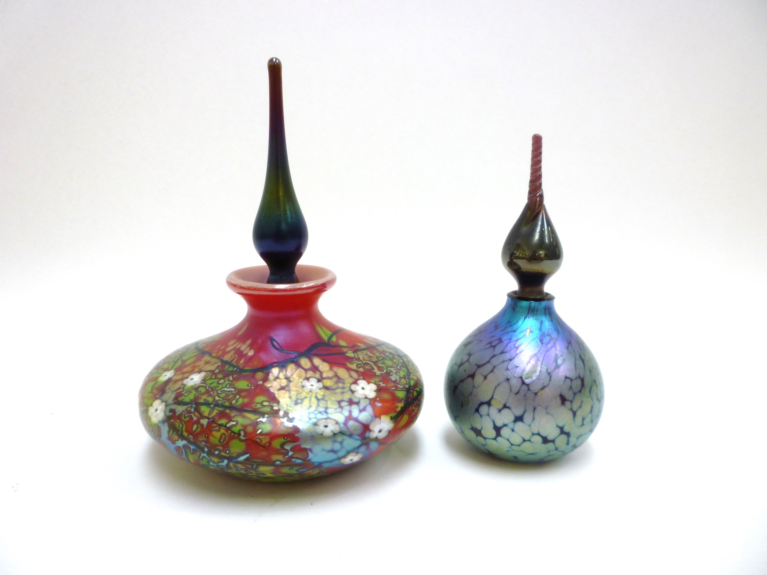 Two Okra glass scent bottles, one in red with floral detail, the other mottled iridescent blue