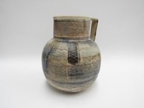 A Studio pottery jug decorated with lined geometric patterns. Indistinctly signed to base, 22.5cm