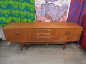 A G-Plan teak sideboard with four cupboard doors flanking three central drawers. 188cm x 46cm x 72cm