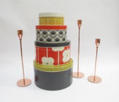 An Orla Kiely set of four metal storage tins and a contemporary trio of tapering form candlesticks