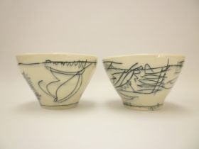 A pair of studio pottery bowls, white ground with black line detail, Indistinctly signed to bases.