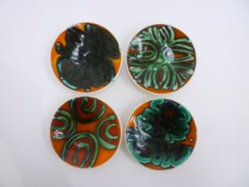 Four Poole Delphis pin dishes in orange, green and black colourways, black back stamps to three, one