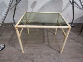 A 1970's glass topped side table with faux bamboo metal legs, 40cm high, 50cm long