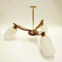 A three branch teak and brassed metal ceiling light with white shades