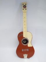 A vintage Elvis Presley toy guitar by Selcol, the brown, cream and burgundy plastic four string