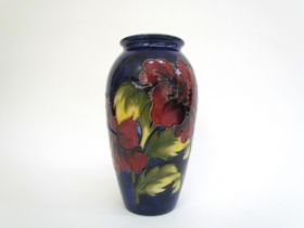 A Moorcroft Hibiscus pattern vase, deep red on a dark blue ground, 18.5cm tall