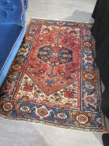 A Persian hand knotted rug, red ground with navy foliate border, 200cm x 132cm