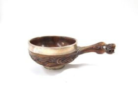 A carved wooden drinking vessel, the handle as a mythical creature, with white metal bands, 22cm