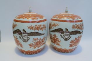 A pair of large ceramic lidded pots / containers with eagle armorial crests, floral detail, 34cm