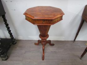 A reproduction burr walnut sewing table, the octagonal top over a faceted column to a carved