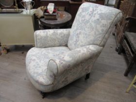 Circa 1900. A "Howard & Sons" style country house armchair, the scroll arms and bow front seat on