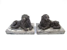 A pair of bronze sculptures of recumbent lions, on marble bases, each 13.5cm long